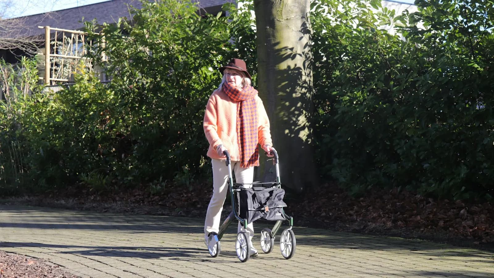 Oudere vrouw loopt buiten met een rollator
