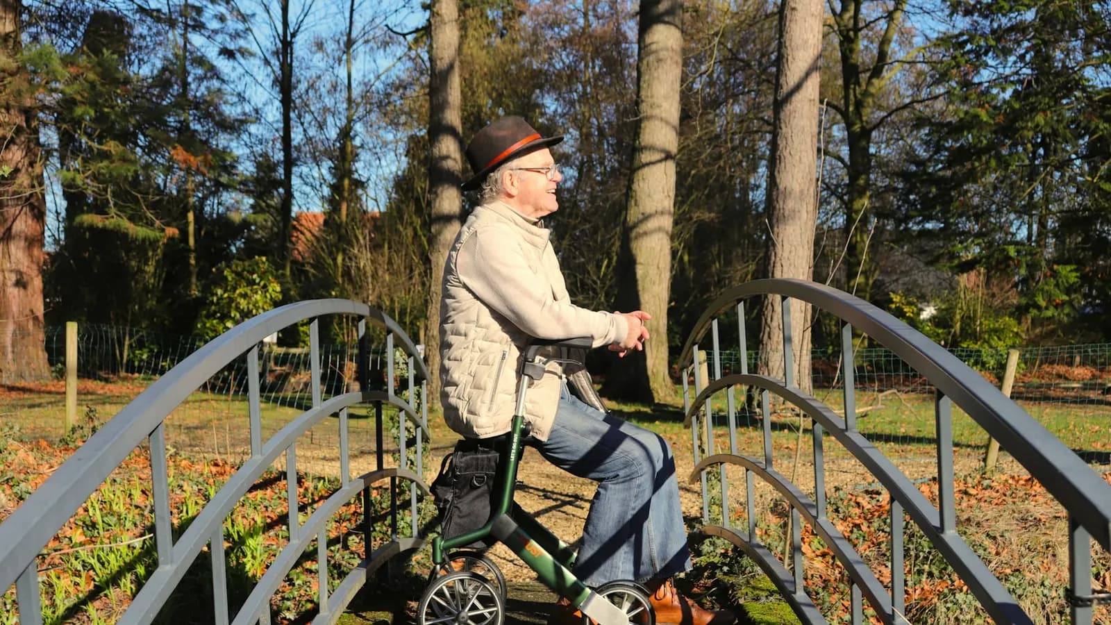 Oudere man rust met rollator op een brug